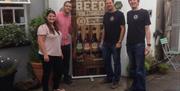 Staff standing beside a beer promotion stand