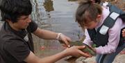A person helping a child hold a fish they just caught