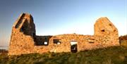 Image of the ruins at sunset with the light of the sun shining onto the remnants of the building