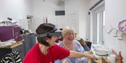 Two women seated at jewellery table and laughing