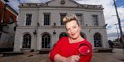 Miss Scarlett holds a magnifying glass at the doorway of The Old Market House, Bangor