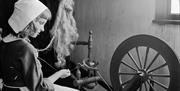 A girl sat at a spinning wheel, spinning