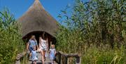 A family walking out of the Crannog roundhouse at WWT Castle Espie.