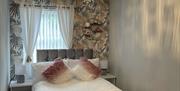 Bedroom 2 double bed at window in front of door.  Patterned wallpaper velvet grey headboard white bedside tables with bedside lamps.  Round hanging go