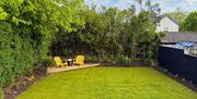 Enclosed lawned garden with seating area and mature trees.
