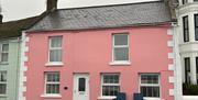 A pink house with a bench in front of it.