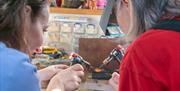 Two ladies with small torches melting down some gold in contemporary studio