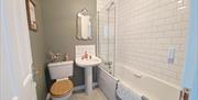 Main Bathroom with shower over bath. Colour scheme is green and pink