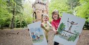 Two children holding poster boards of illustrations by Quentin Blake, in the grounds of WWT Castle Espie
