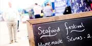 Chalkboard listing items for sale at a previous Seafood Festival