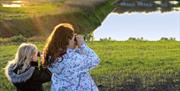 two young girls looking through binoculars over the wetlands