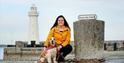 a photo of a woman and a dog in front of donaghadee lighthouse