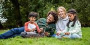 Family sitting on the grass making a structure with branches