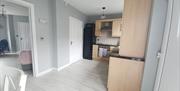 Kitchen from back door with double opening into living room. Sitting at table you can see the sea while eating