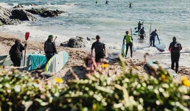 a photo of a group of people with paddle boards by the coast