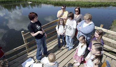 a photograph of a group of people standing next to a lake