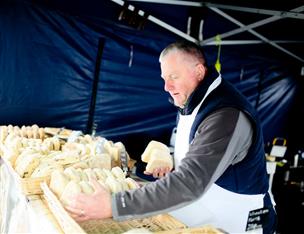 Baker placing out fresh breads at a market stall