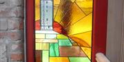 Stained glass window of lighthouse, fields and sunrays