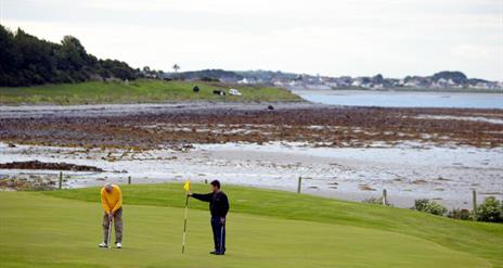 Photo of two golfers in play with stunning scenery to the background