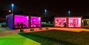 The pods lit at night in neon pink