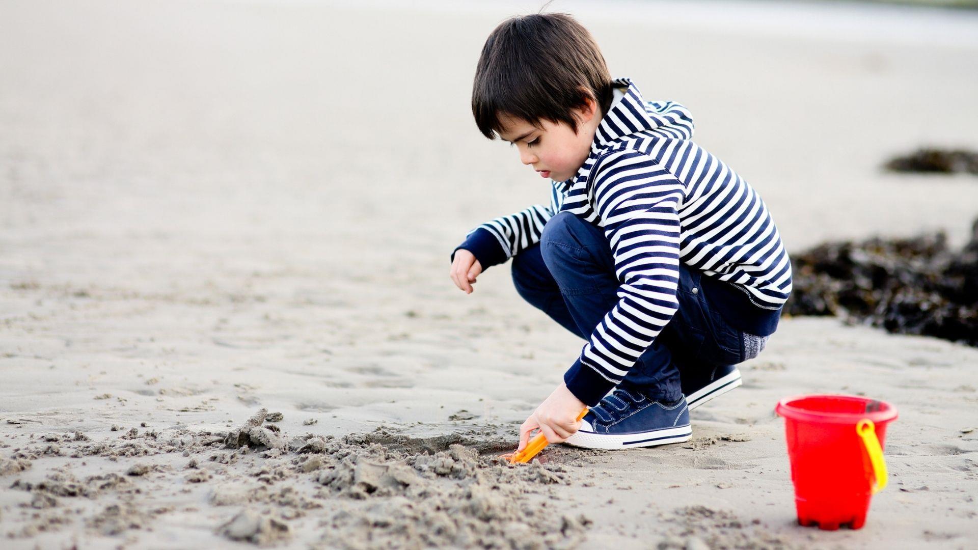 a photo of a boy digging a hole at the beach
