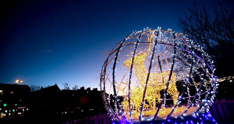Photograph of Christmas decor in Bangor of a Reindeer and its young lit up within a globe of fairy lights