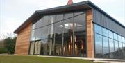 Photo of building exterior made up of mostly glass with a clear view of the beautiful copper pot stills central to the open plan floorspace