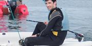 a photo of a man on a boat in a wetsuit