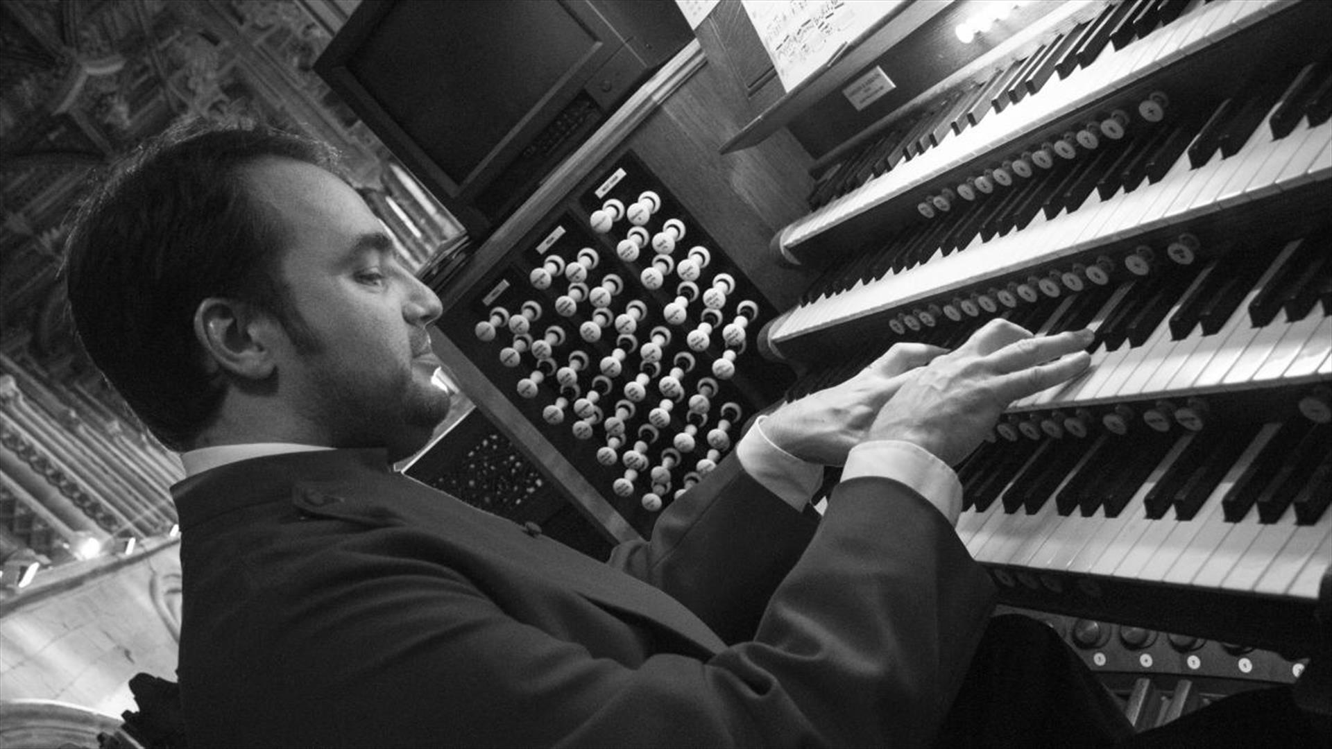 Black and white photo of musician Daniel Cook performing on the organ