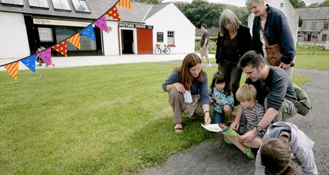 A family of three generations looking over a map within the grounds of the Folk Museum