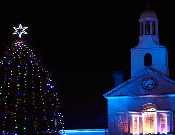 A photograph of Newtownards Christmas Tree lit at night with Ards Arts Centre in the backdrop