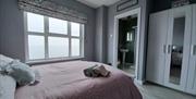 Front bedroom showing view into ensuite shower room. Triple white wardrobes. Seaview