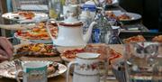 Photo of a treat filled table including pizza, tea pots and more