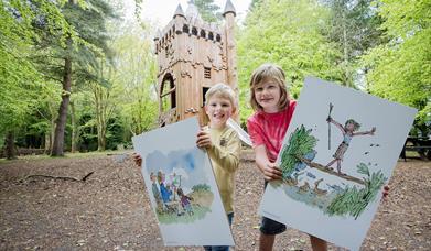 Two children holding poster boards of illustrations by Quentin Blake, in the grounds of WWT Castle Espie