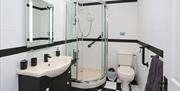 Fully fitted bathroom with shower, sink and toilet. Hand rails and shower seat fixtures.