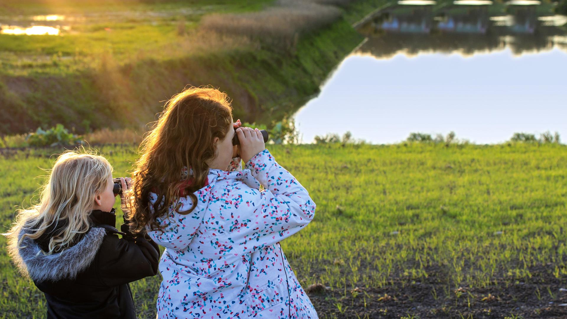 two young girls looking through binoculars over the wetlands