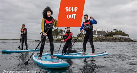 A group enjoying Stand Up Paddleboarding on Strangford Lough with overlapping text that says Sold Out