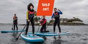 A group enjoying Stand Up Paddleboarding on Strangford Lough with overlapping text that says Sold Out