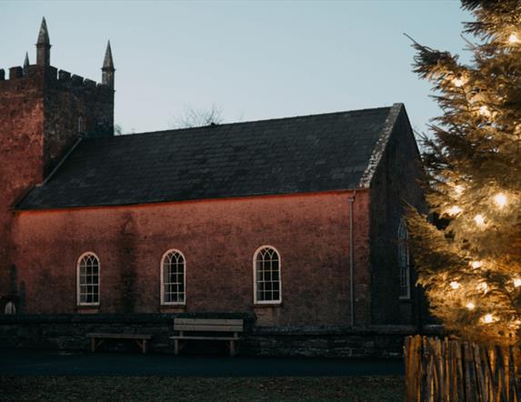A picture of Kilmore Church at Ulster Folk Museum with a christmas tree at night