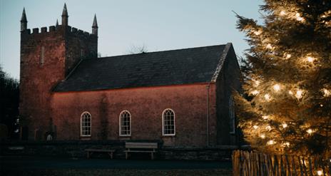 A picture of Kilmore Church at Ulster Folk Museum with a christmas tree at night