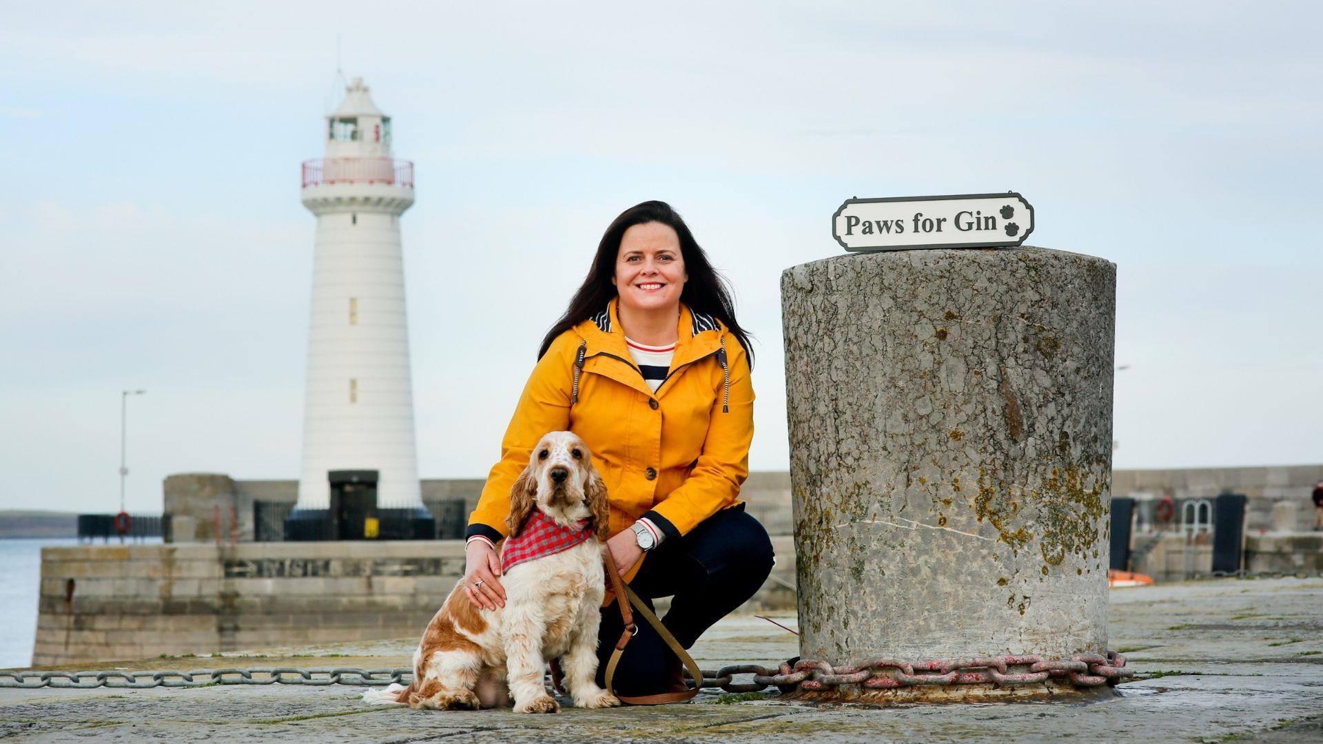 a photo of a woman and a dog in front of donaghadee lighthouse