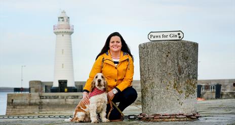 a photo of a woman and a dog in front of donaghadee lighthouse