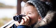 A child taking in the view through binoculars