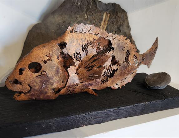 Copper fish on black wood, created by Lake & Oak Coppersmithing artists